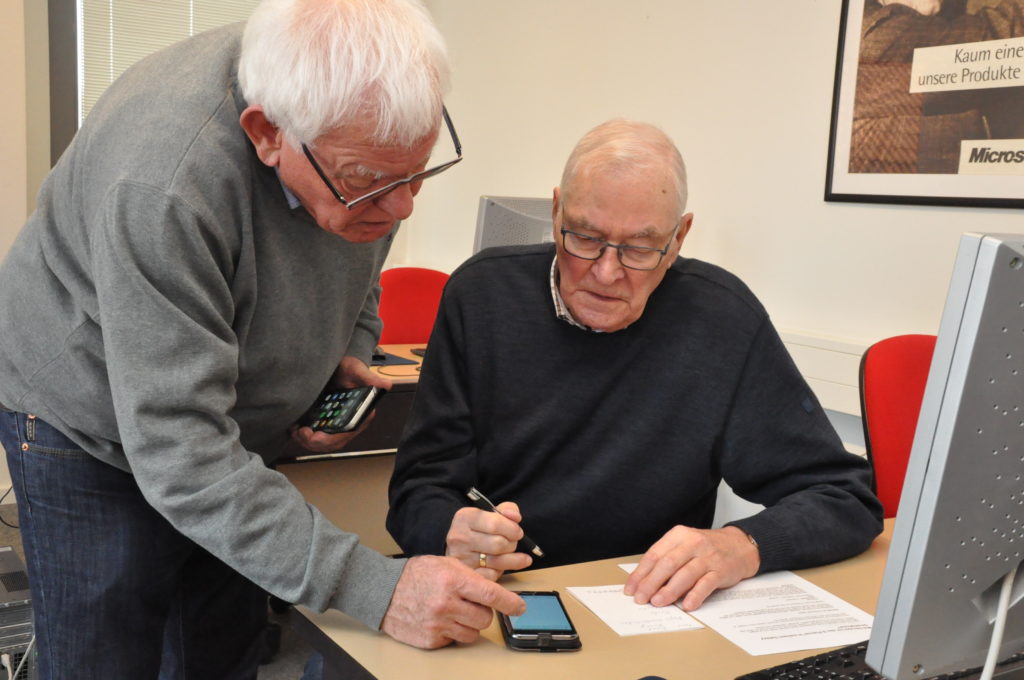 Hans Hogeweg bringt Altbürgermeister Hans Diekmann die Tücken des Smartphones näher. Foto: Stefan Freiwald